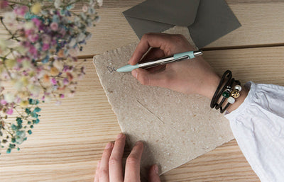 Woman writing a note wearing a leather bracelet with beads